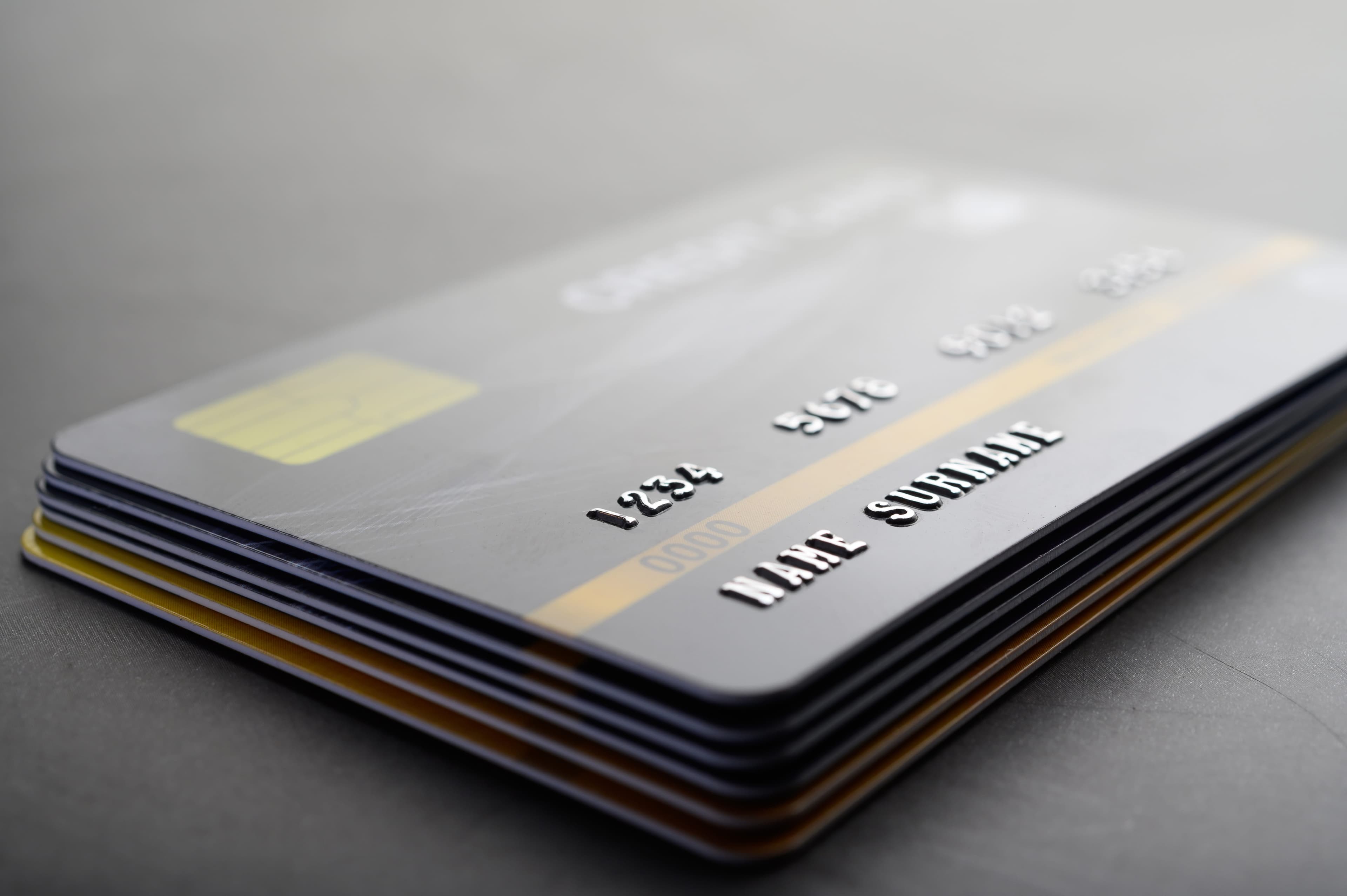 A stack of credit cards on a dark desk